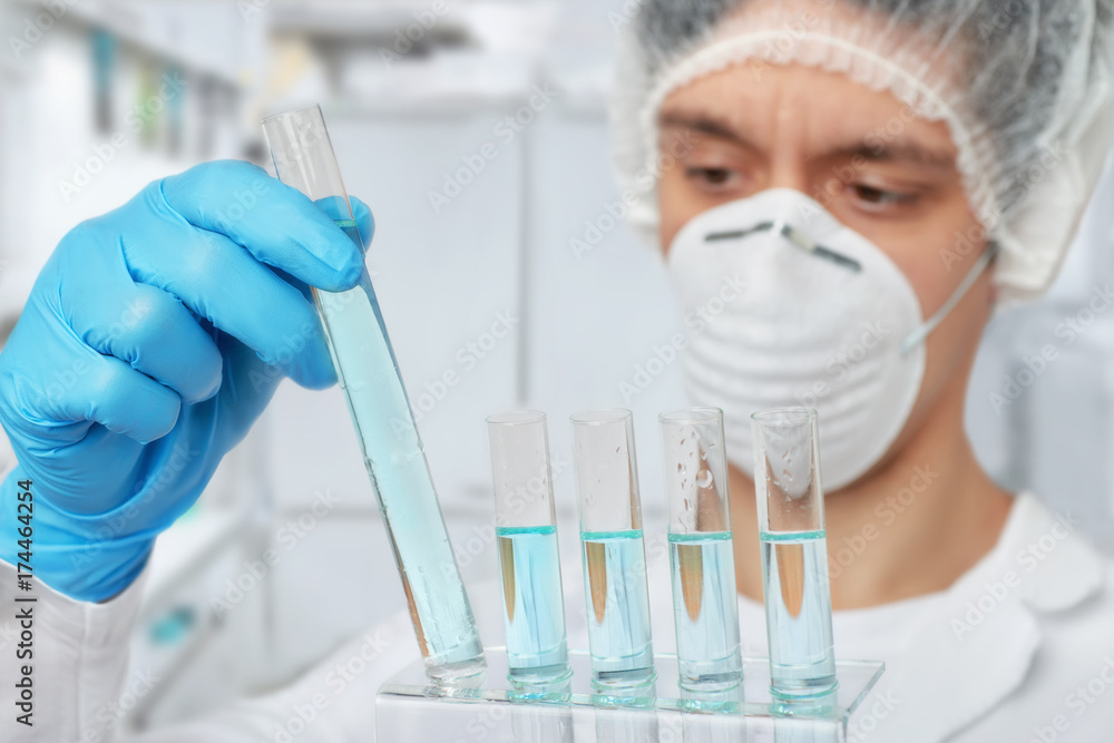Keen scientist in protective wear with liquid samples Keen scientist in protective wear with liquid samples