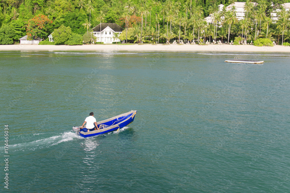 Obraz premium Back of skipper controlling small boat to coast.