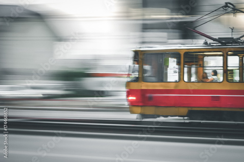 Fast moving red and yellow tram in the city with light on, panning blurry effect