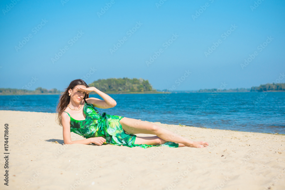 Middle aged stylish woman wear in long silk dress on a beach rest at good sunny day Middle aged stylish woman wear in long silk dress on a beach rest at good sunny day