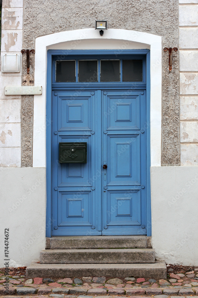 Closed blue door with the mailbox in a stone house