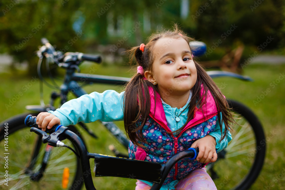Naklejka premium Smiling little girl on a bicycle