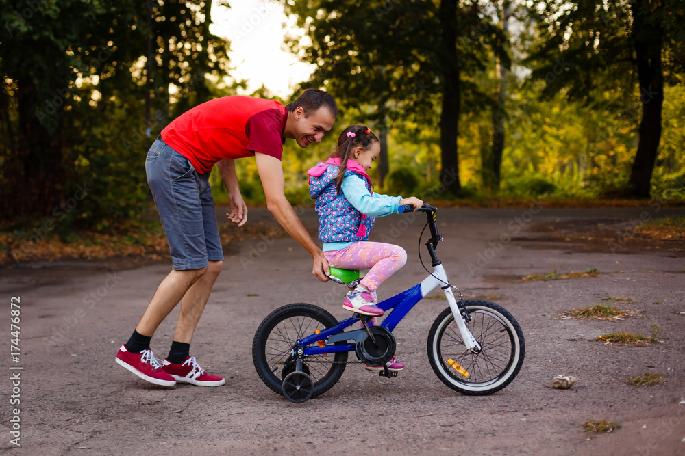 Fototapeta premium Father teaching his daughter to ride a bike
