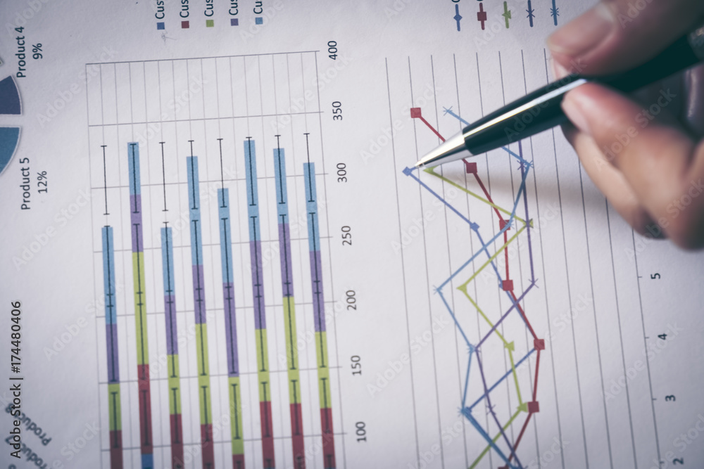 male hands pointing at turnover graph while discussing it on wooden desk in office. male hands pointing at turnover graph while discussing it on wooden desk in office.