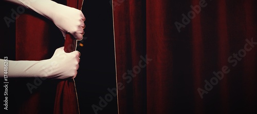 Cropped hands in gloves holding curtain at stage