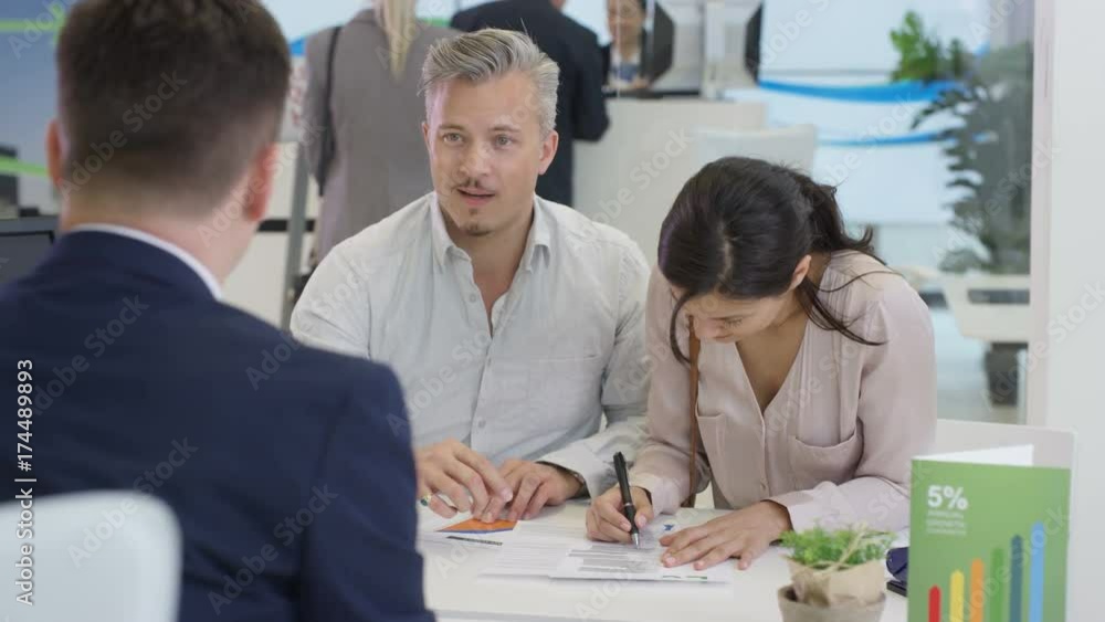 Modern city bank, couple talking to adviser & signing document Modern city bank, couple talking to adviser & signing document