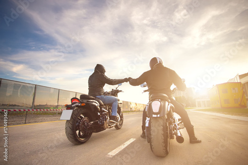 Two bikers ot motocycles handshaking with knuckle on road at sunshine photo