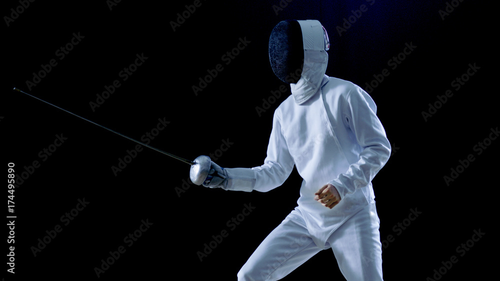 One Professional Fencer is Standing Ready for Fighting. Shot Isolated on Black Background with Cold Tones. One Professional Fencer is Standing Ready for Fighting. Shot Isolated on Black Background with Cold Tones.