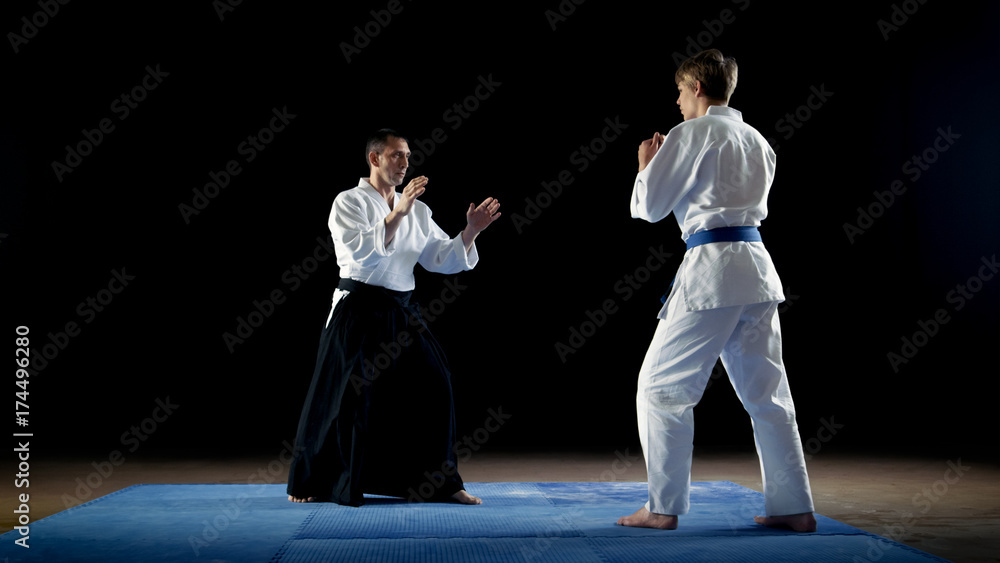 Martial Arts Master Wearing Traditional Samurai Hakamas Teaches Young Student Aikido Technique How To Reflect Fist Blows and Overpower Your Enemy. Shot Isolated on Black Background.
