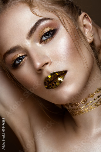 beautiful girl with a golden shiny make-up and stars on her lips. Beauty face. Photo taken in the studio.