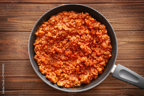 Meat sauce in frying pan on wooden background