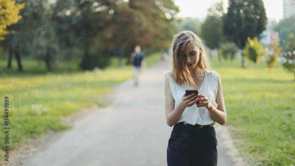 Front view fashion happy woman walking using smart phone mobile city street summer blurred background youth leisure student modern lifestyle technology development media business network texting Front view fashion happy woman walking using smart phone mobile city street summer blurred background youth leisure student modern lifestyle technology development media business network texting