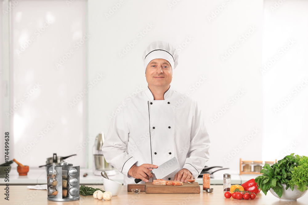 Male chef cutting meat in kitchen