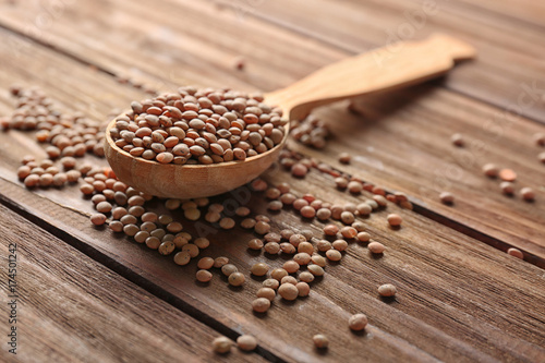 Spoon with healthy lentils on wooden background