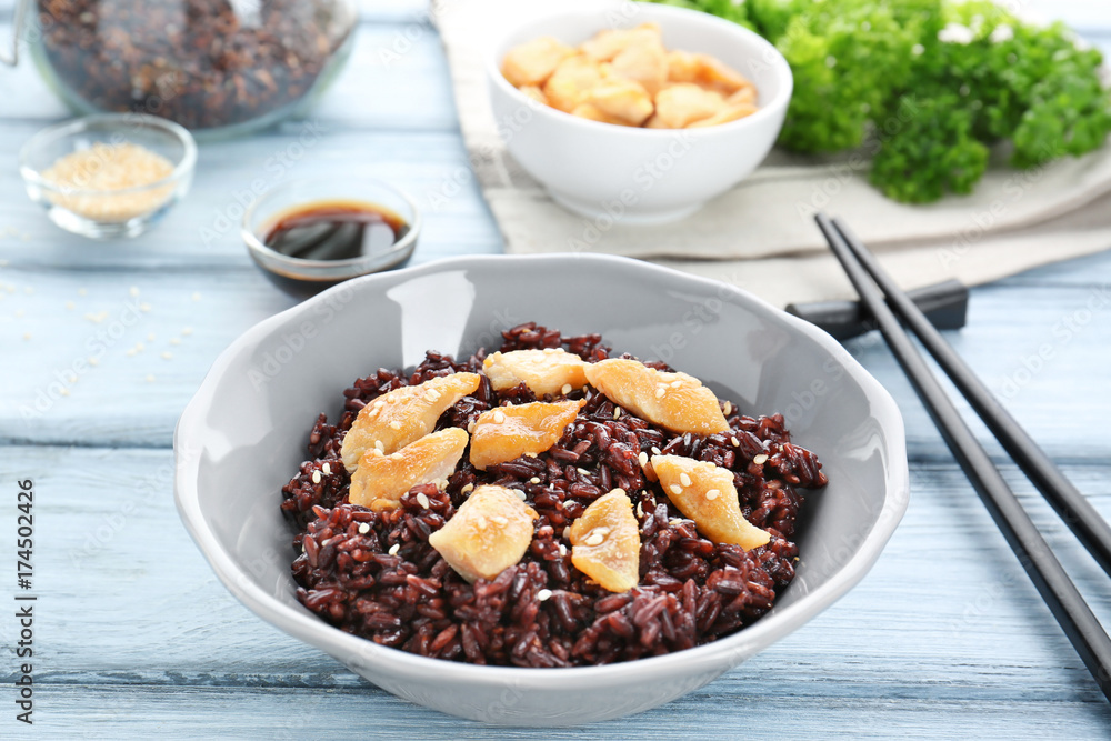 Plate with black rice on wooden table