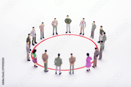 Miniature business people standing in circle over backdrop or background.