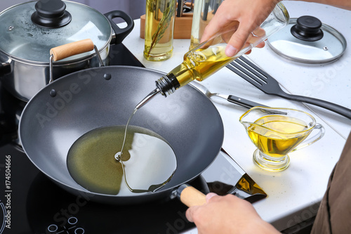 Canvastavla Man pouring cooking oil from bottle into frying pan on stove