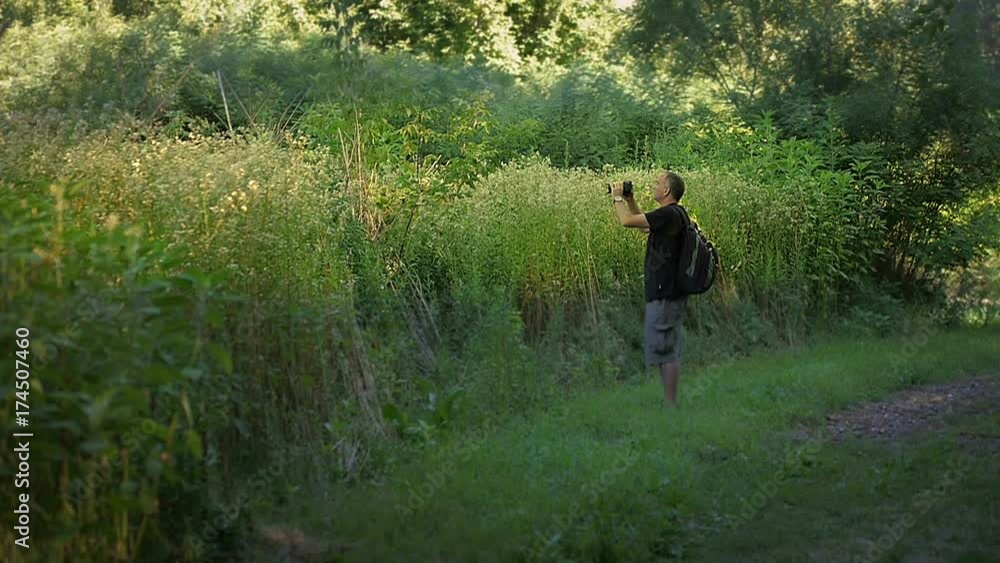 Nature photographer taking above the shoulder photo in tall grass Nature photographer taking above the shoulder photo in tall grass
