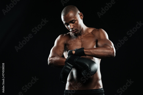 Young boxer putting on boxing gloves before training