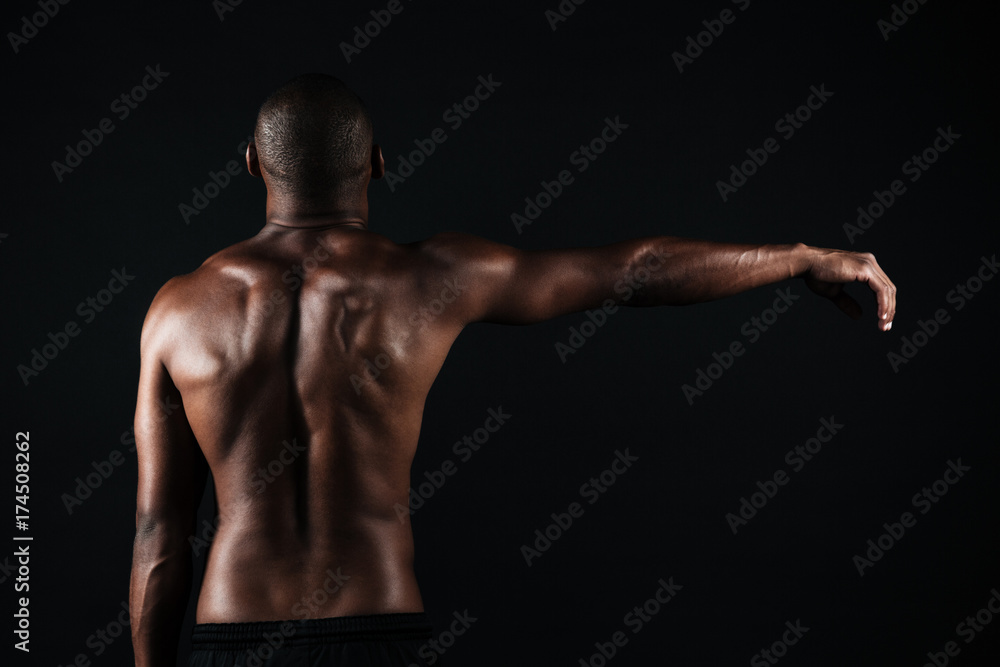 Back view photo of half-naked muscular sports man, with right hand up