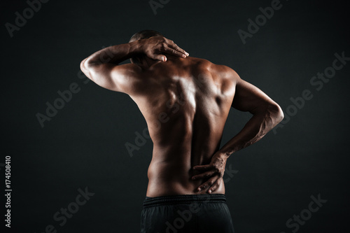 Back view of young african sports man feeling pain in his back