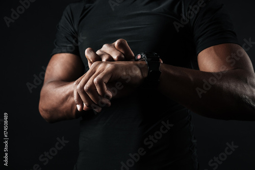 Close-up photo of african man in black t-shirt check out time at black wristwatch