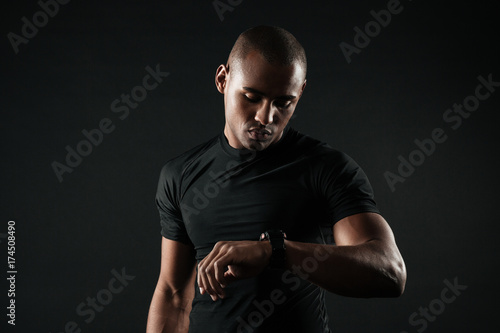 Closeup portrait of serious afro american sports man checking time on his hand