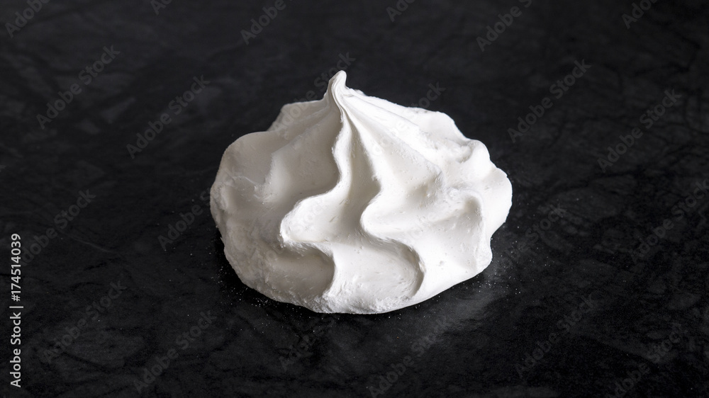 Sweet white meringue is isolated on a dark background. Sweet white meringue is isolated on a dark background.
