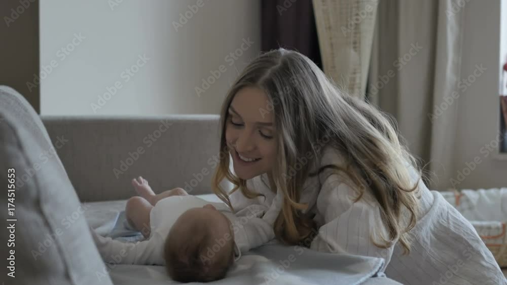 Mother putting baby on sofa Mother putting baby on sofa