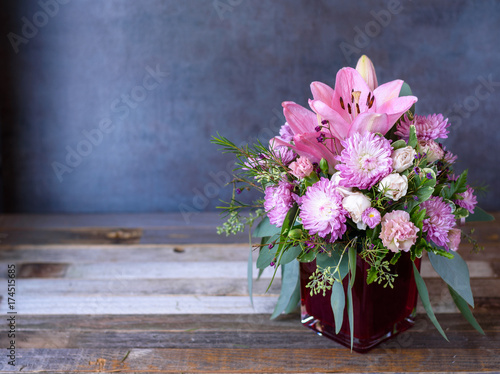 Beautiful colorful pink lily flower bouquet on rustic wooden background. Copy space.
