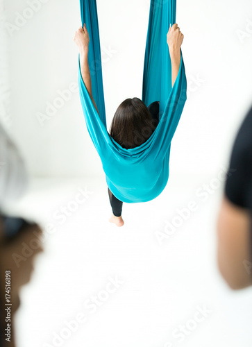 Training a young girl with a fly yoga elements in a white gym