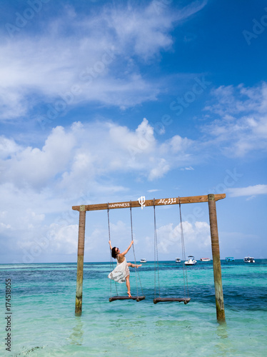lady with beach dress poses on the swing at the beach