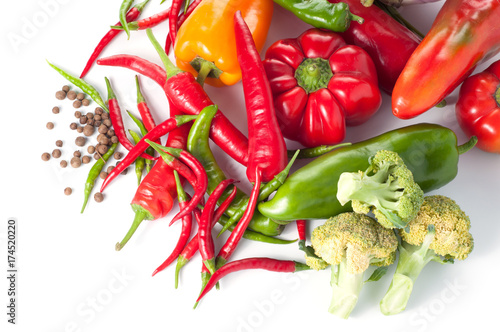 Harvest of different peppers and vegetables on a white background photo