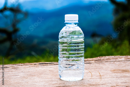Mineral water bottle on a wooden table in forest,mountains view.Water bottles on a wooden table with a background of mountain with green tree.
