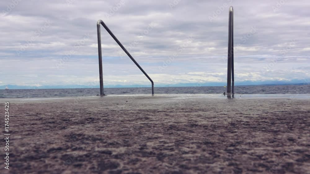 Sea waves and foam on seaside coastline concrete pier
