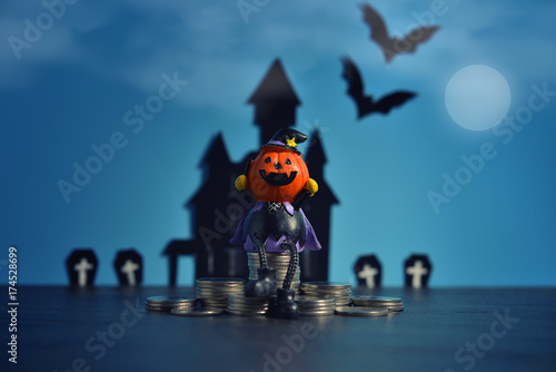 Halloween pumpkins jack-o-lantern with money coin stack growing business on dark blue background. Happy Halloween.