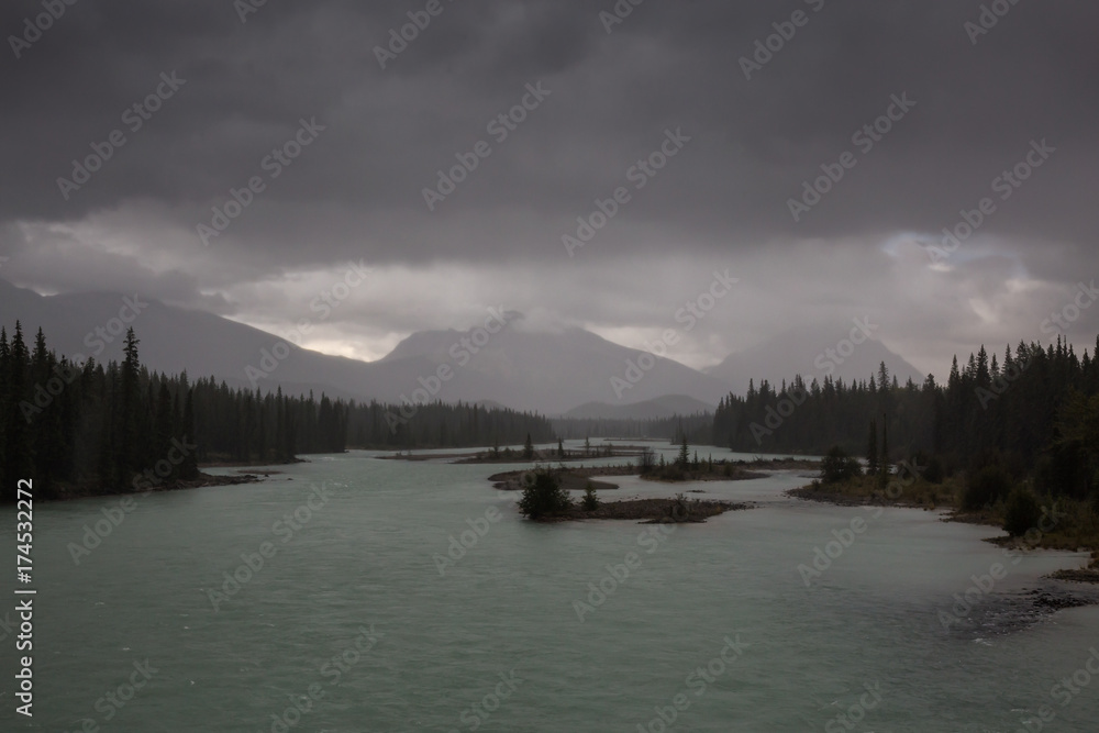 Dark rainy clouds over Athabasca River on Icefields Pkwy in Jasper National Park, Alberta, Canada.