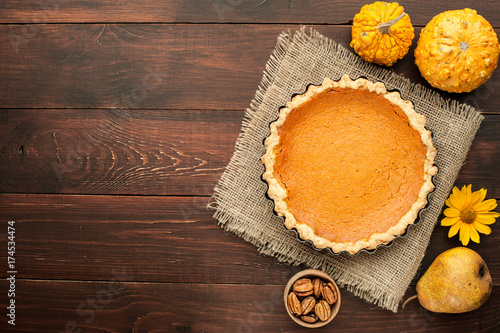 pumpkin homemade pie at wooden background arranged with food ingredients top view