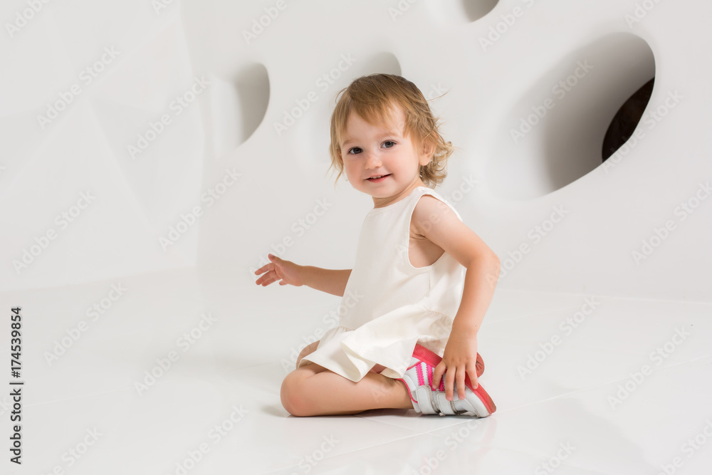 Smiling little girl sitting on the floor on a white background Smiling little girl sitting on the floor on a white background