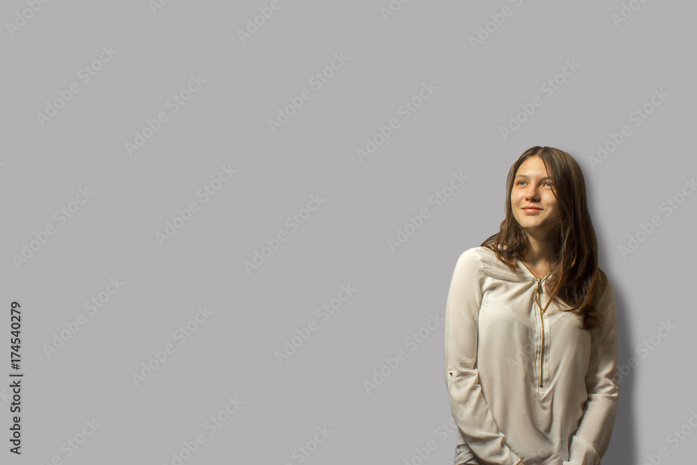 Portrait of young beautiful student girl smiling and looking away. isolated on a gray background. the concept of confidence in the future. a lot of copy space. Portrait of young beautiful student girl smiling and looking away. isolated on a gray background. the concept of confidence in the future. a lot of copy space.