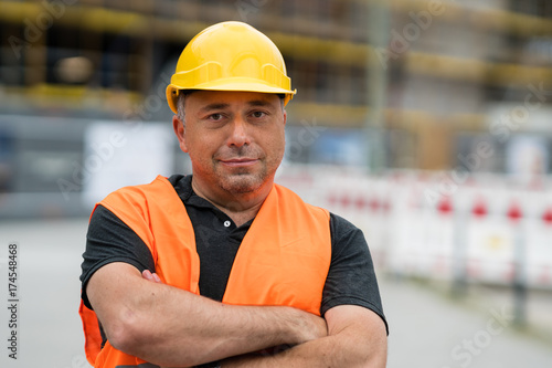 Happy and satisfied engineer with crossed arms on construction site
