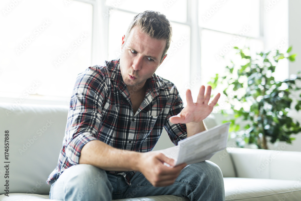 Shocked man holding some documents on sofa livingroom Shocked man holding some documents on sofa livingroom