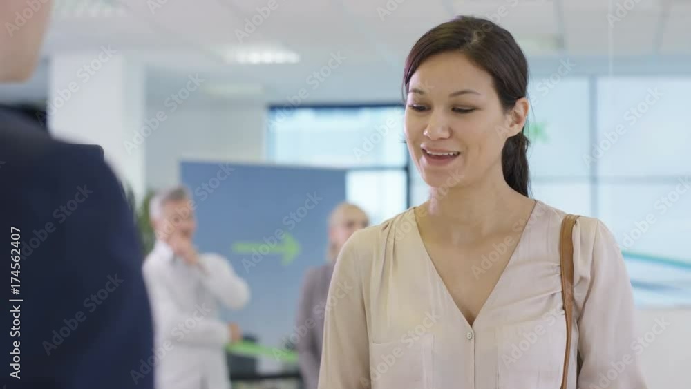 Friendly bank worker at service desk assisting queue of customers Friendly bank worker at service desk assisting queue of customers