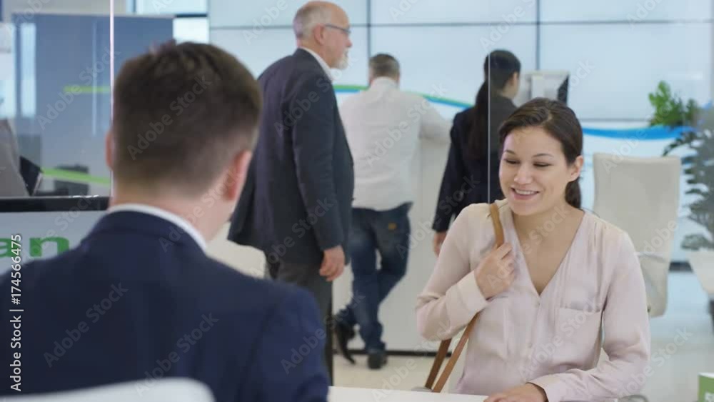 Modern city bank, man assisting customer & getting signature on document Modern city bank, man assisting customer & getting signature on document