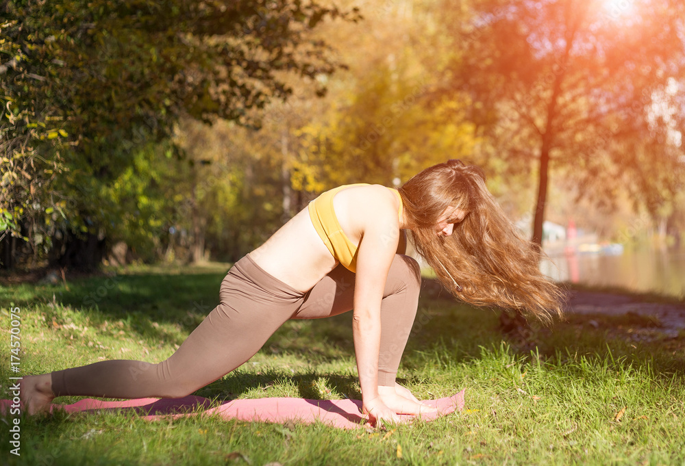 Fototapeta premium Portrait of young woman in autumn city park. Sport girl doing yoga outside