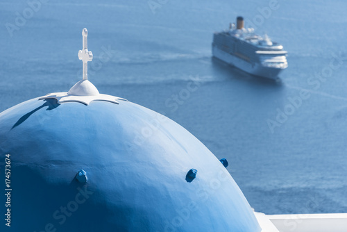 Santorini, the typical blue dome of Orthodox church and in the background a large cruise ship in the Aegean Sea