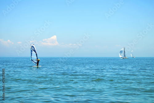 Windsurfing. Lonely surfer exercising on blue water.