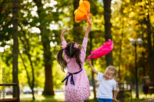 two happy little schoolgirls jumping and throwing a backpack photo