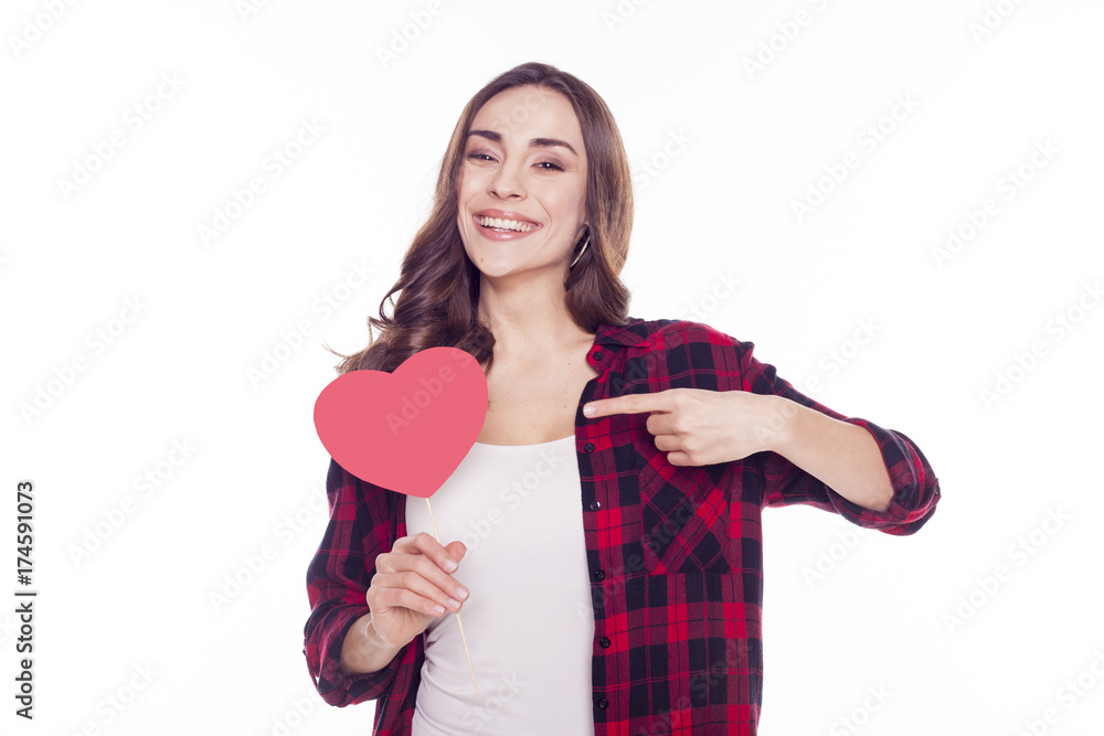 Young beautiful brunette girl smiles and holds in her hands a red paper heart isolated on white Young beautiful brunette girl smiles and holds in her hands a red paper heart isolated on white