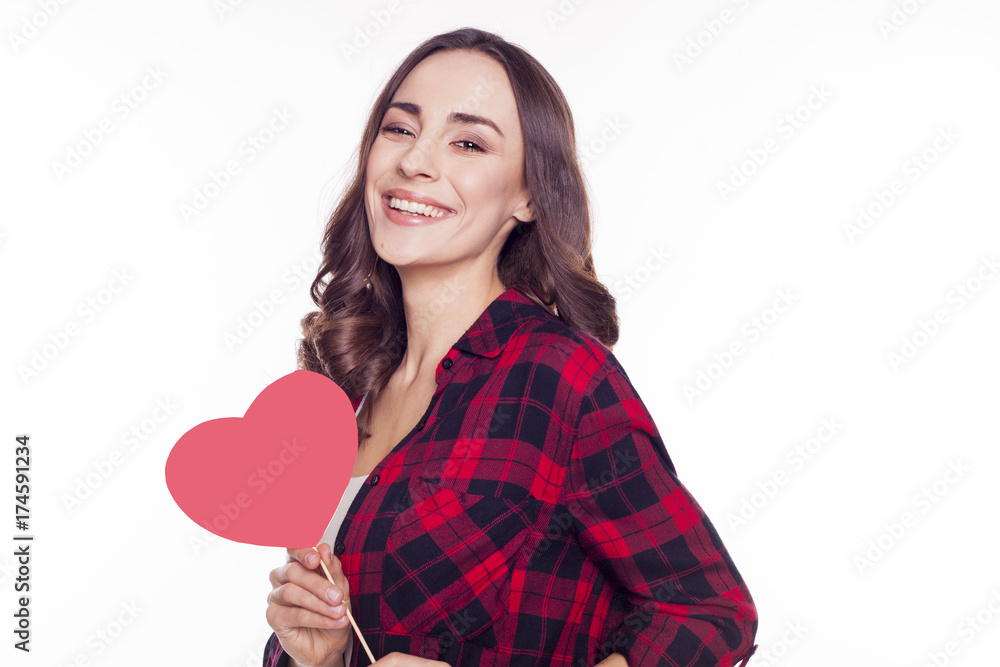 Young beautiful brunette girl smiles and holds in her hands a red paper heart isolated on white Young beautiful brunette girl smiles and holds in her hands a red paper heart isolated on white
